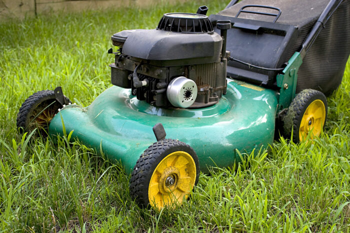 Gas powered green lawn mower sitting in grass